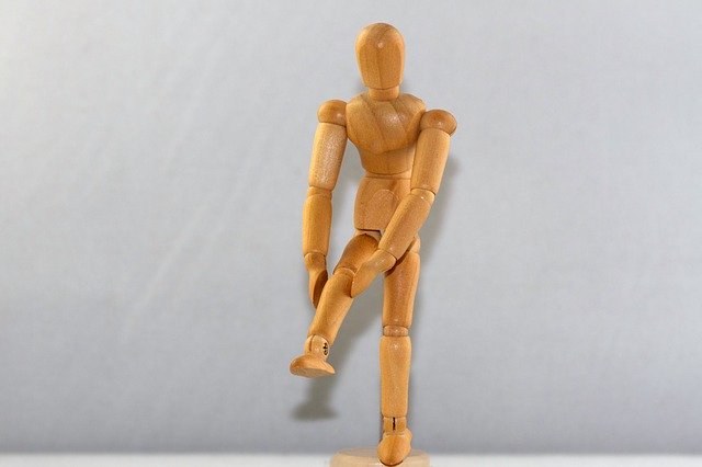 膝を痛そうに押さえている人型の人形の画像