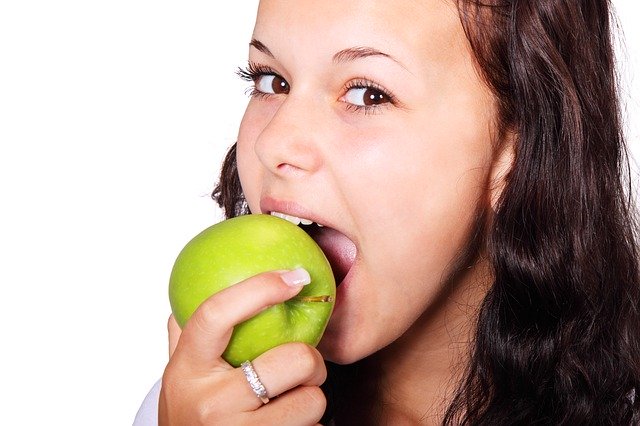 女性がリンゴをかじっている画像